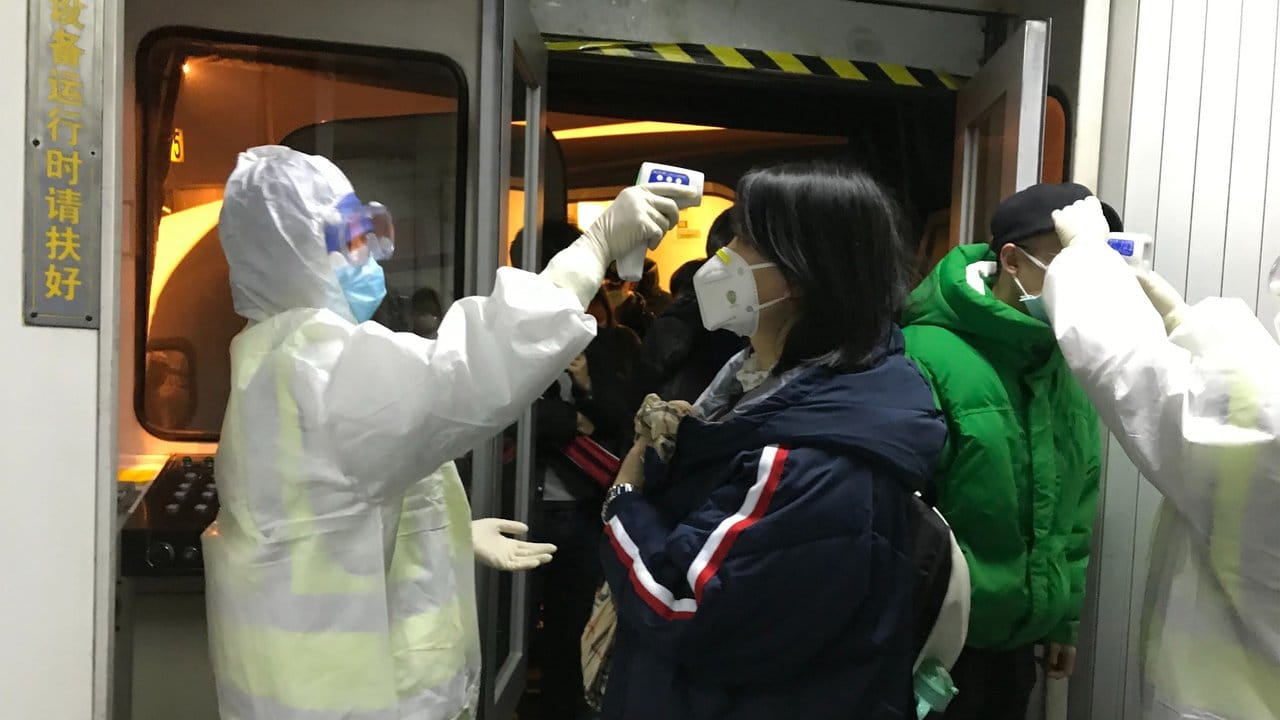 Gesundheitsbeamte kontrollieren in Peking die Körpertemperatur aus Wuhan angereister Passagiere. Gesundheitsbeamte kontrollieren in Peking die Körpertemperatur aus Wuhan angereister Passagiere.