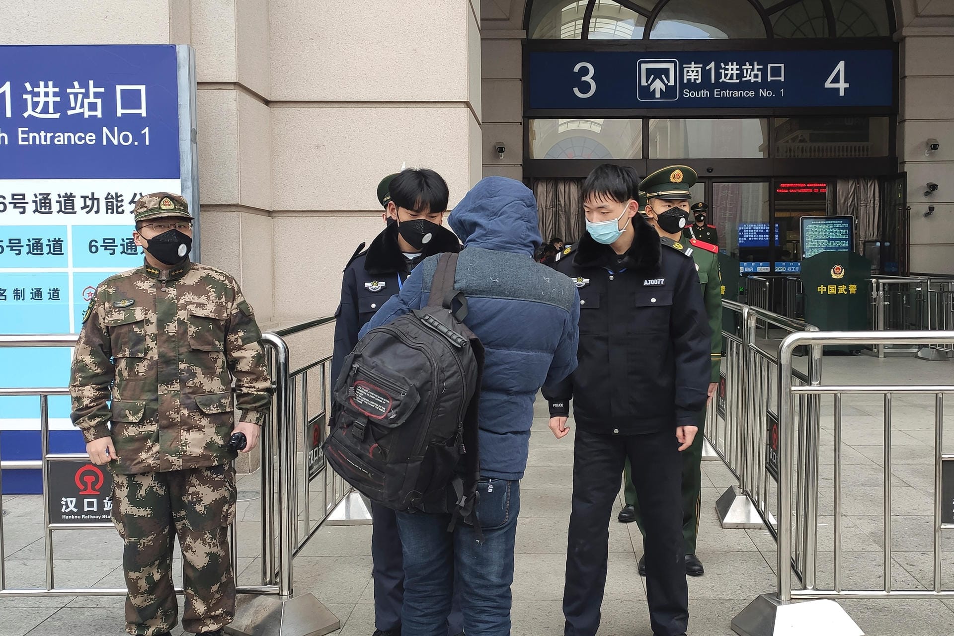 Sicherheitsbeamte kontrollieren eine Person am Eingang des Bahnhofs Hankou in Wuhan.