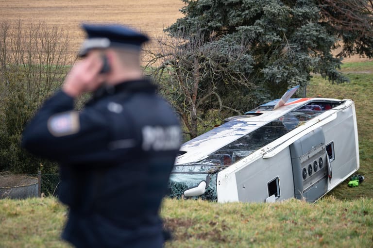 Ein Polizist steht neben dem verunglückten Schulbus in Berka vor dem Hainich: Bei dem Unfall sind zwei Kinder ums Leben gekommen.