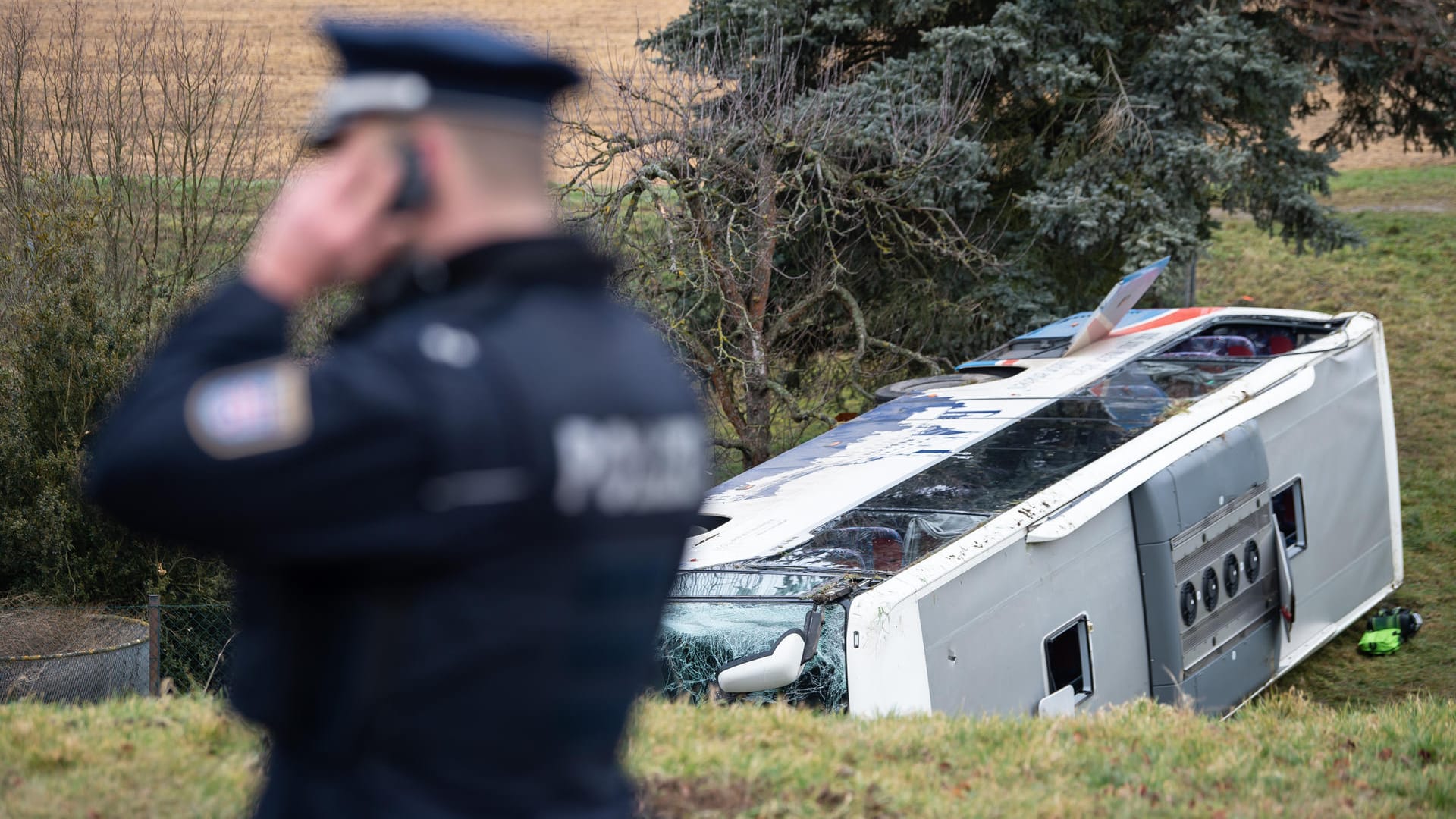 Ein Polizist steht neben dem verunglückten Schulbus in Berka vor dem Hainich: Bei dem Unfall sind zwei Kinder ums Leben gekommen.