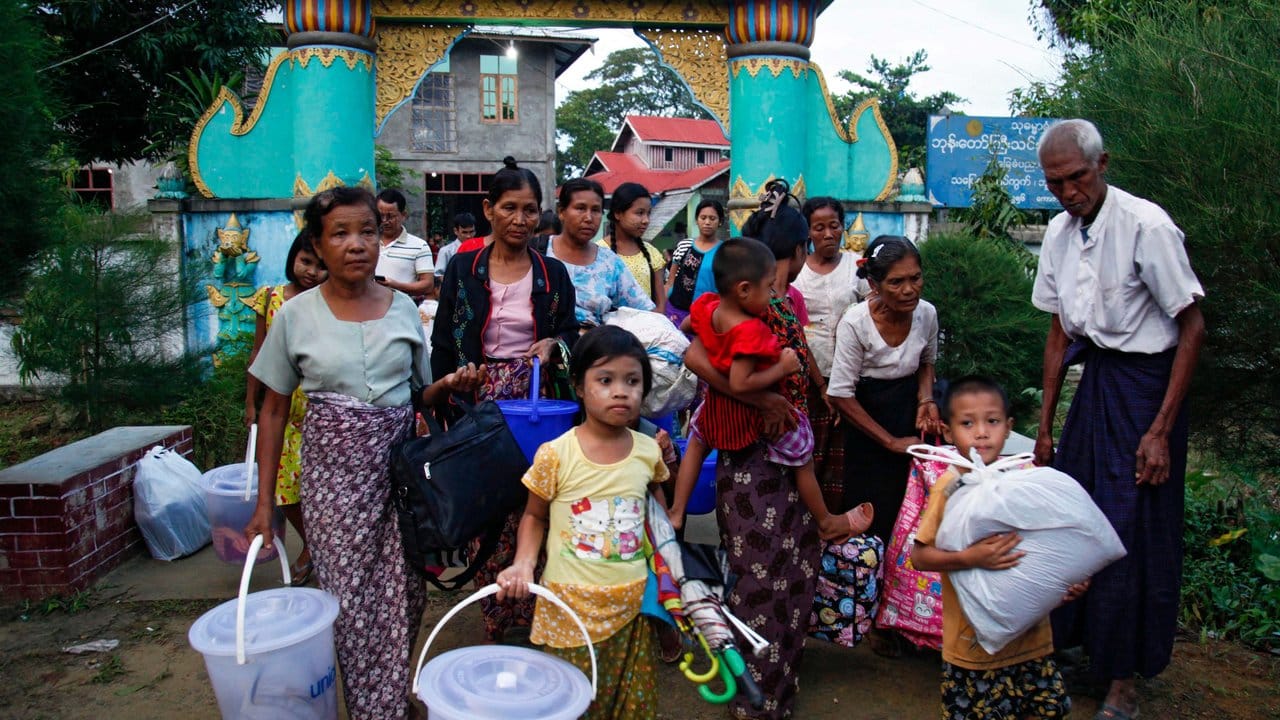 Rohingya, die aus dem Kampfgebiet geflohen sind, tragen ihr Hab und Gut bei der Ankunft in einem Kloster.
