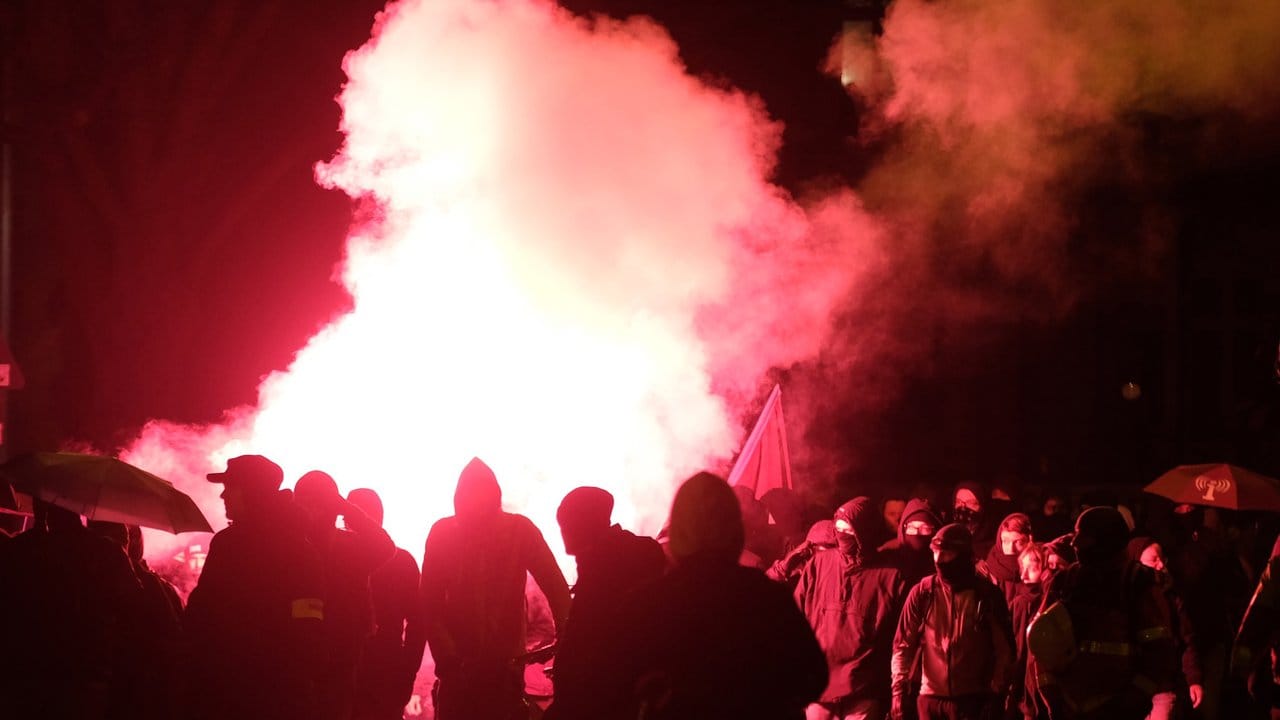 Teilnehmer der linken Demonstration zünden Pyrotechnik.