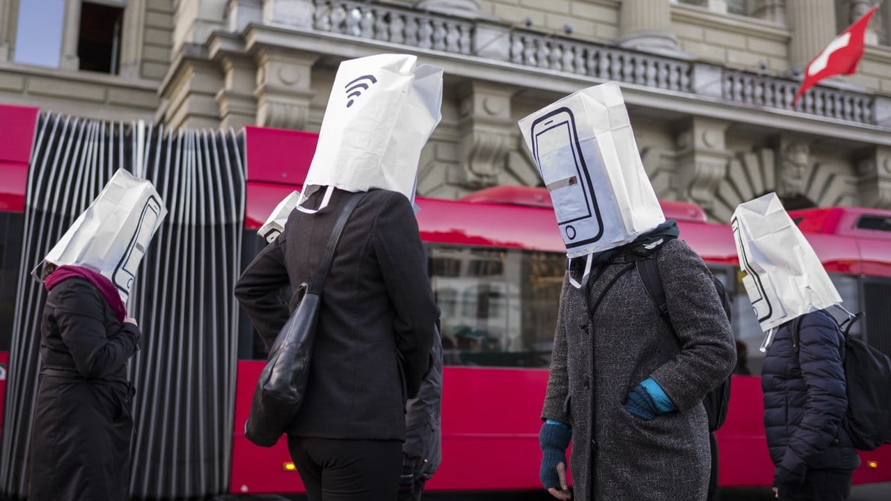 Aktivisten mit Papiertüten auf dem Kopf, auf denen Mobiltelefone abgebildet sind, warnen während der Nationalratssitzung vor dem Ausbau des Mobilfunknetzes auf den 5G Standard.