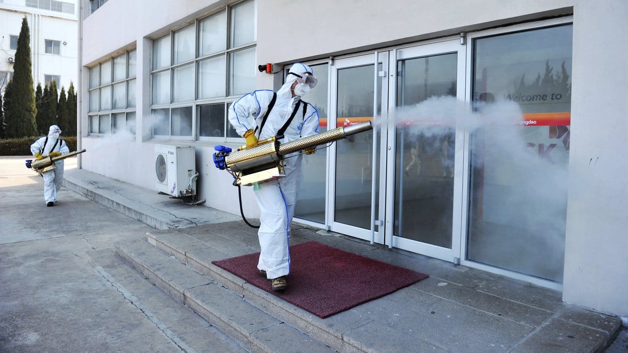 Arbeiter in Schutzkleidung desinfizieren ein Geschäft in der Millionenstadt Qingdao im Osten Chinas. Arbeiter in Schutzkleidung desinfizieren ein Geschäft in der Millionenstadt Qingdao im Osten Chinas.