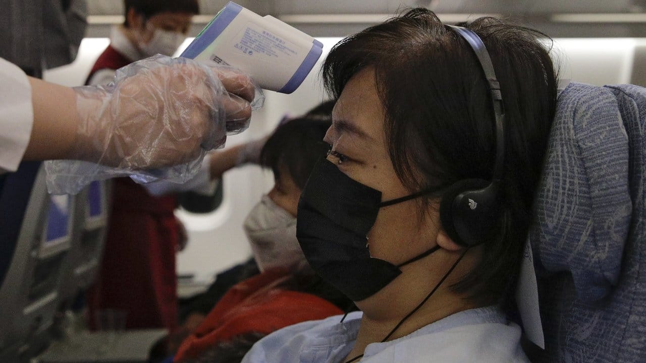 Flugbegleiter messen zur Vorsicht die Körpertemperaturen der Passagiere auf einem Air-China-Flug von Melbourne nach Peking. Flugbegleiter messen zur Vorsicht die Körpertemperaturen der Passagiere auf einem Air-China-Flug von Melbourne nach Peking.