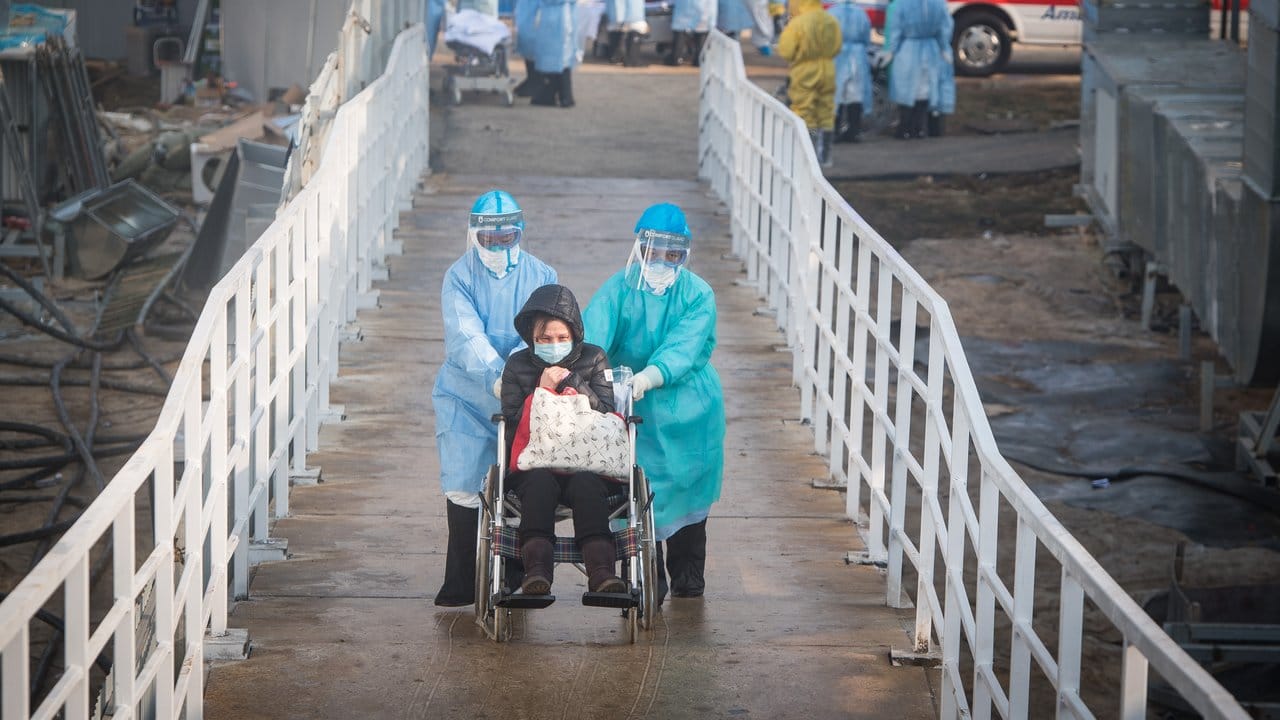 Mediziner helfen Corona-Patienten in Wuhan beim Umzug in die Isolierstationen eines neuen Behelfskrankenhauses mit rund tausend Betten. Mediziner helfen Corona-Patienten in Wuhan beim Umzug in die Isolierstationen eines neuen Behelfskrankenhauses mit rund tausend Betten.