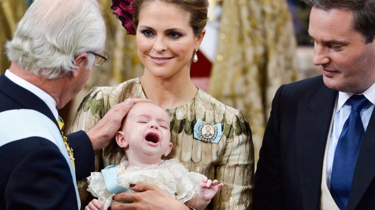 Schwedens König Carl Gustaf (l) bei der Taufe seinen Enkels Prinz Nicolas Paul Gustaf, der in den Armen von Prinzessin Madeleine liegt, rechts der Vater Christopher O'Neill. Schwedens König Carl Gustaf (l) bei der Taufe seinen Enkels Prinz Nicolas Paul Gustaf, der in den Armen von Prinzessin Madeleine liegt, rechts der Vater Christopher O'Neill.