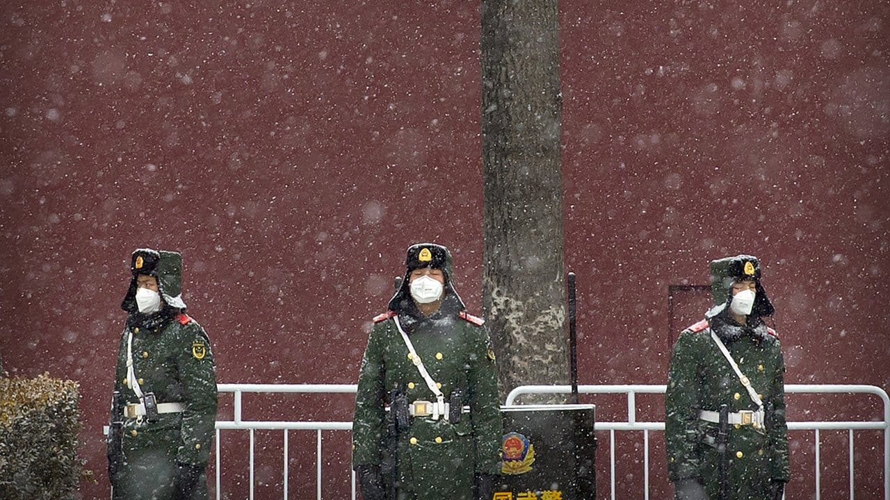 Chinesische Polizisten stehen bei Schneefall in der Nähe des Platzes des Himmlischen Friedens und tragen einen Mundschutz.