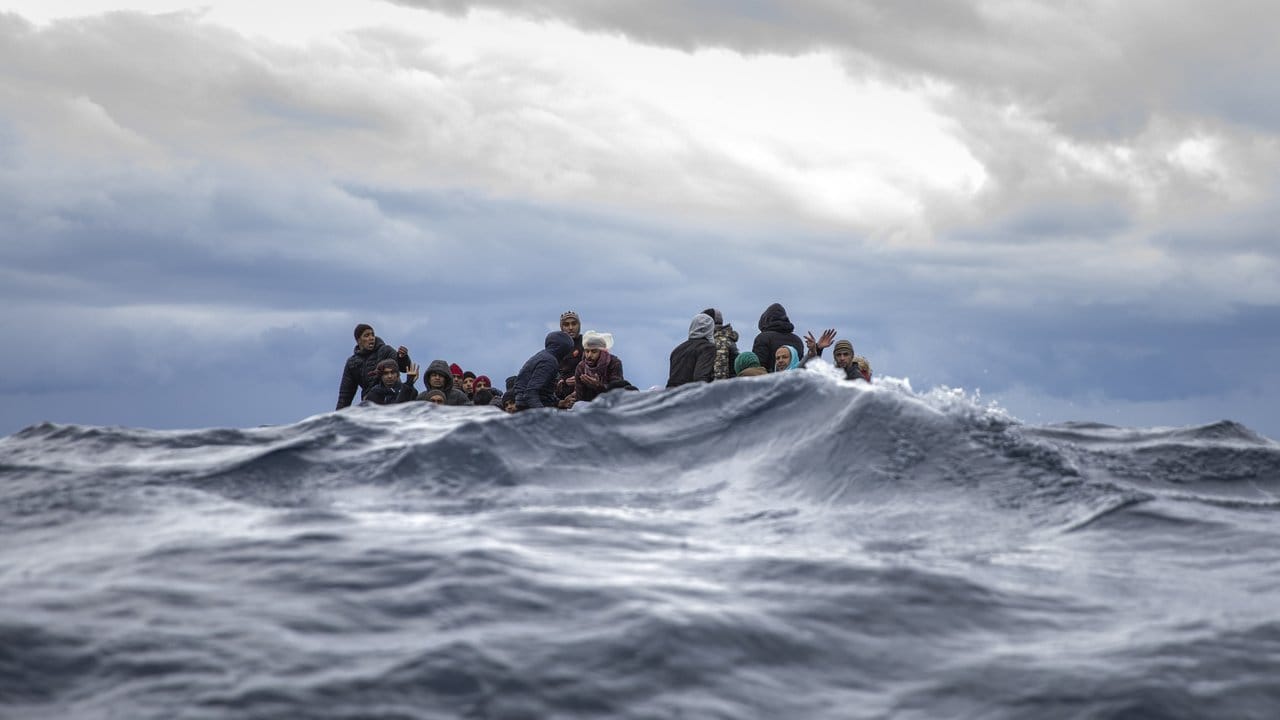 Rettung in letzter Sekunde: Männer aus Marokko und Bangladesch sitzen in einem überfüllten Holzboot vor der libyschen Küste, als sich ihnen Hilfsarbeiter der spanischen Hilfsorganisation "Open Arms" nähern.