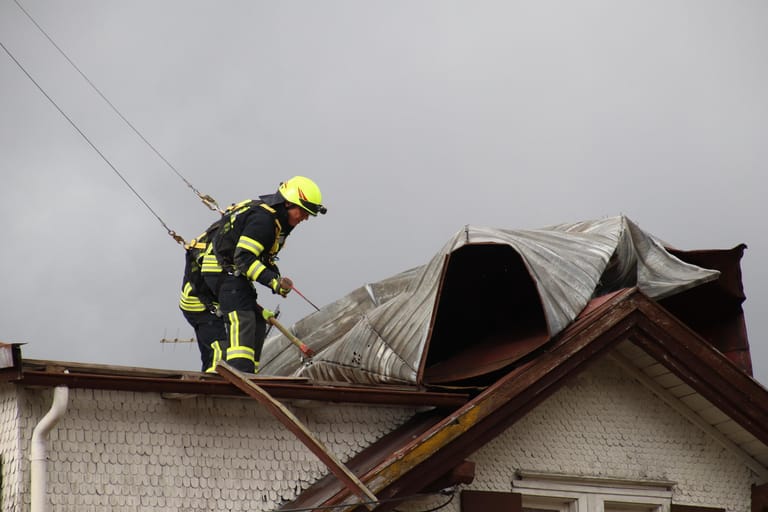 Ein Feuerwehrmann sichert ein Dach, das während des Sturmtiefs "Sabine" in Sonthofen, Bayern, beschädigt wurde.