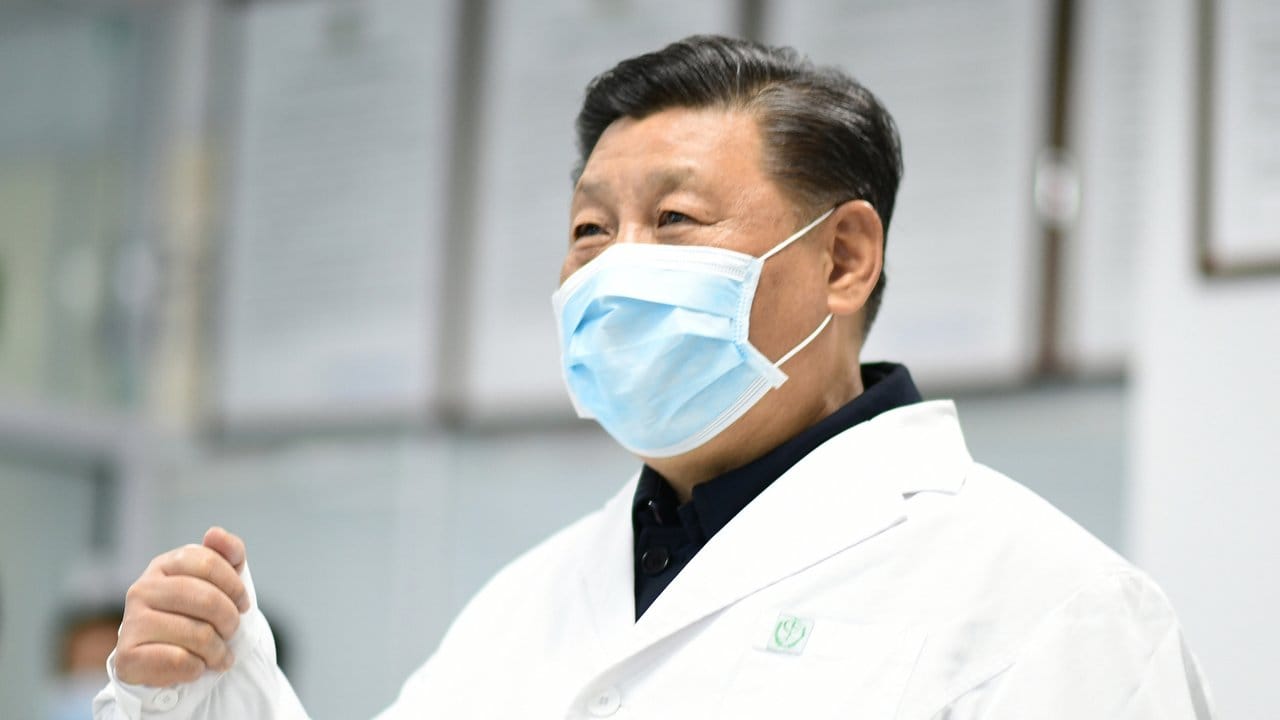 Chinas Präsident Xi Jinping trägt einen weißen Kittel und Mundschutz.