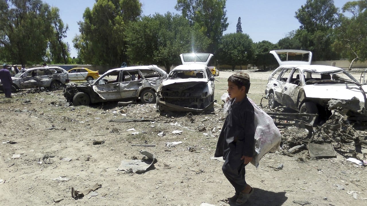 Alltag in Afghanistan: Ein kleiner Junge geht nach einem Selbstmordanschlag an Autowracks vorbei.