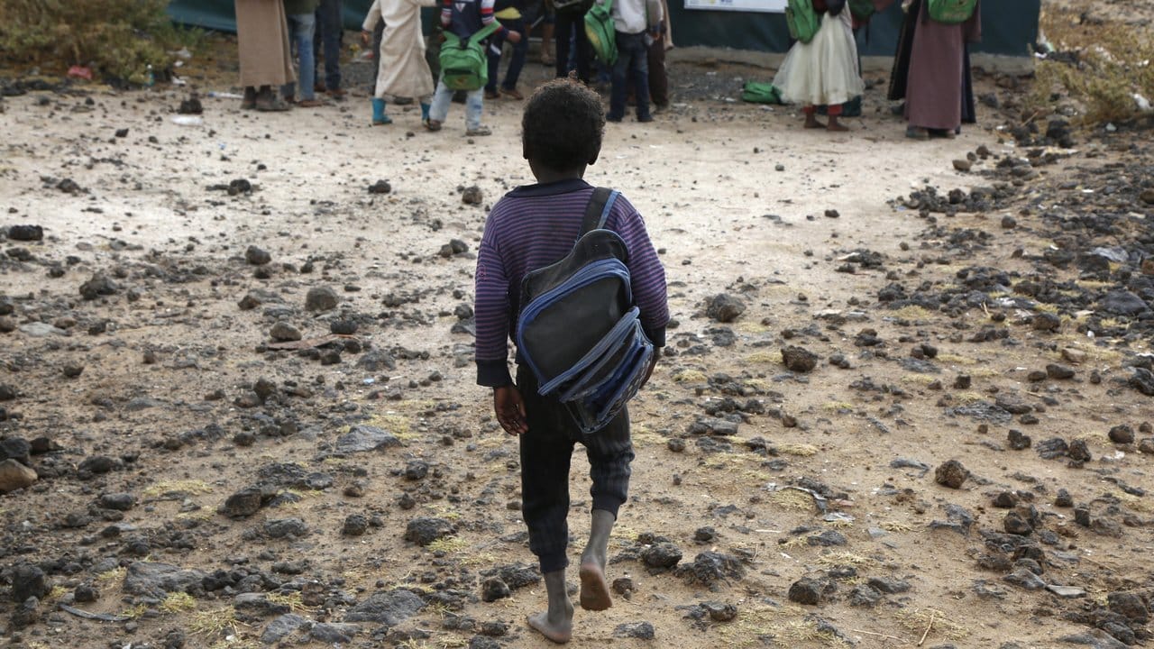 Ein jemenitisches Flüchtlingskind geht in einem Lager am Rande von Sanaa barfuß zur Schule.