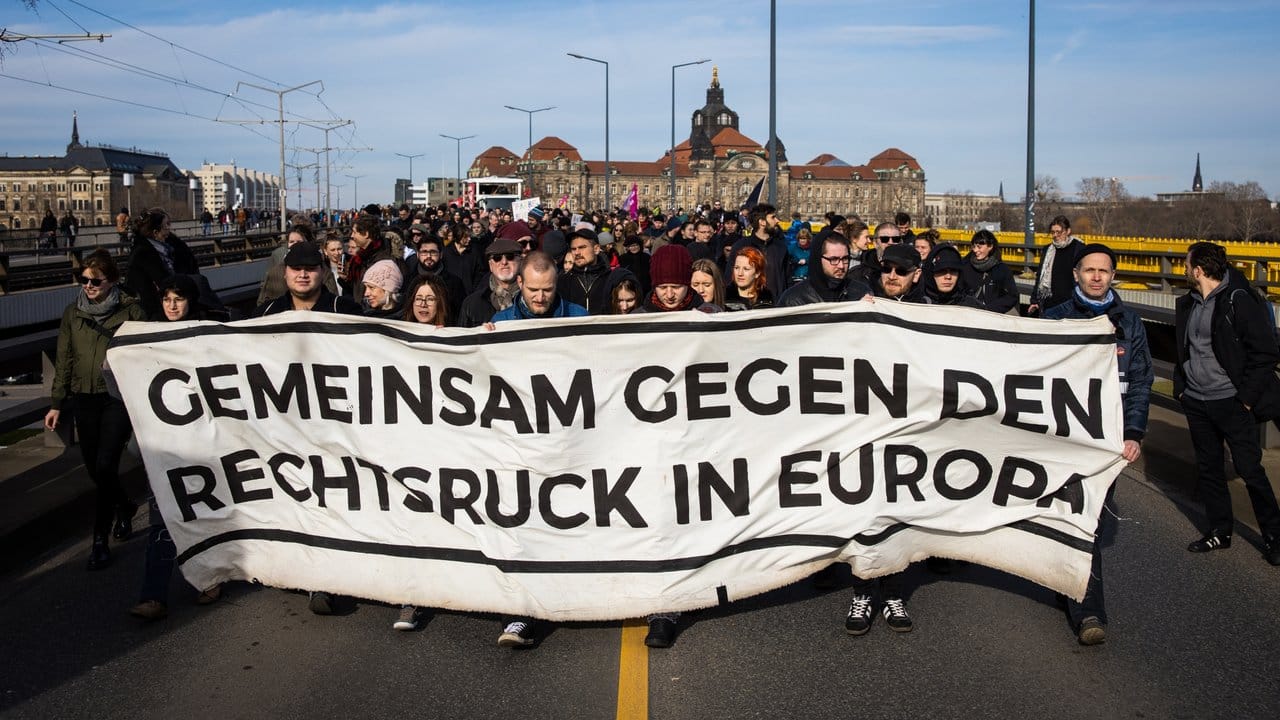 Gegendemonstranten ziehen mit einem Banner durch Dresden.