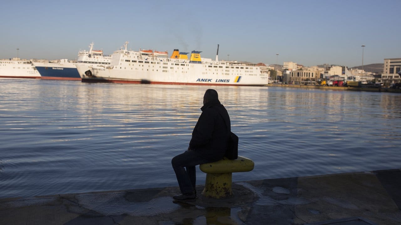Ein Mann sitzt am Kai im Hafen von Piräus.
