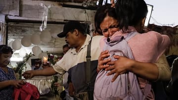 Zwei Frauen umarmen sich und weinen auf der Totenwache eines ermordeten siebenjährigen Mädchens.