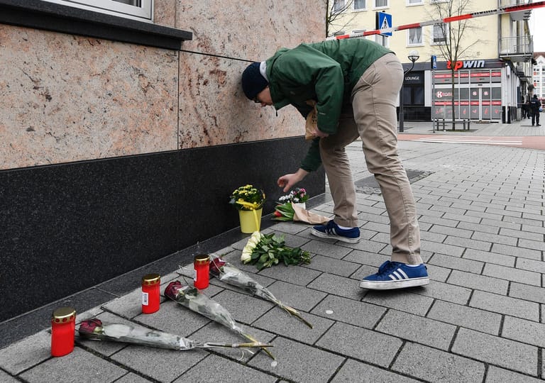 Ein Mann legt am Tatort unweit der Hanauer Innenstadt Blumen nieder.