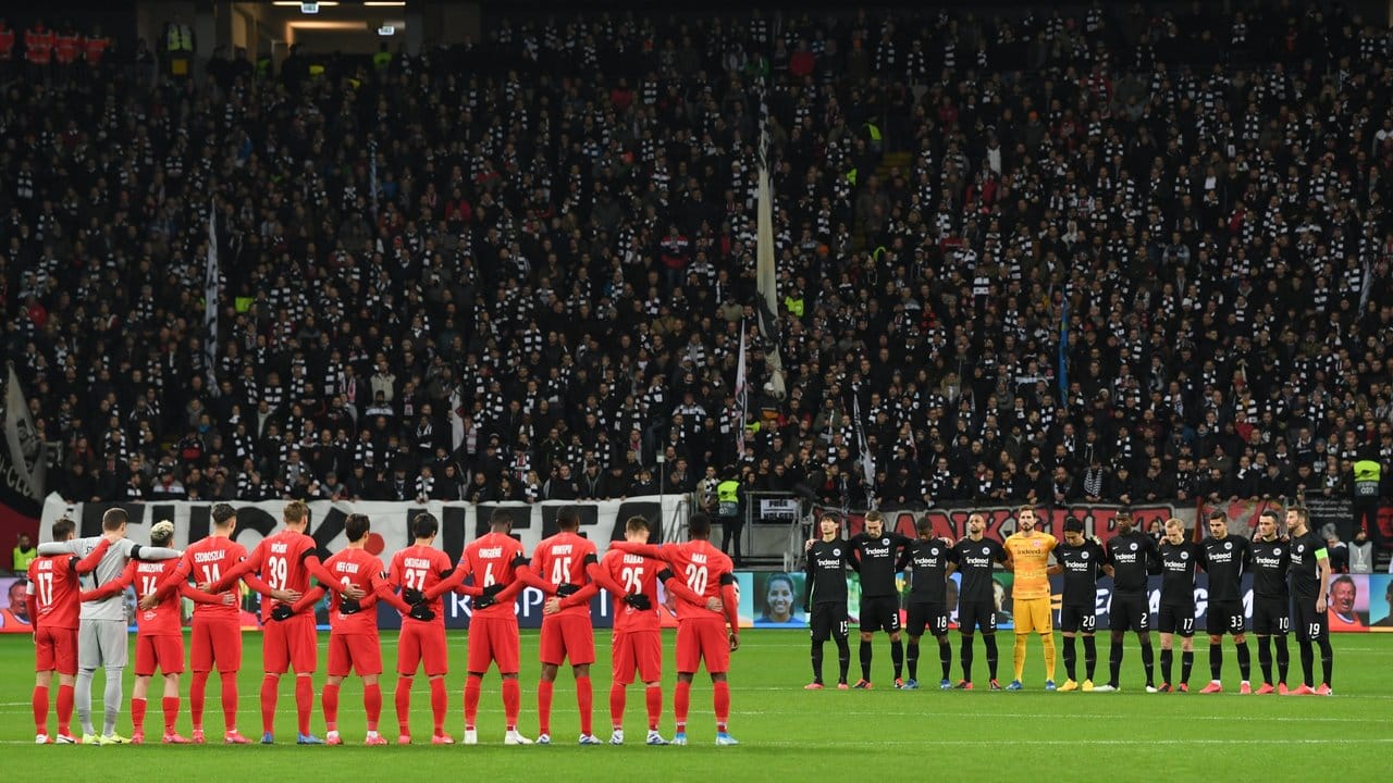 Die Spieler von Eintracht Frankfurt (r) und RB Salzburg stehen bei einer Schweigeminute für die Opfer des Anschlags in Hanau zusammen.