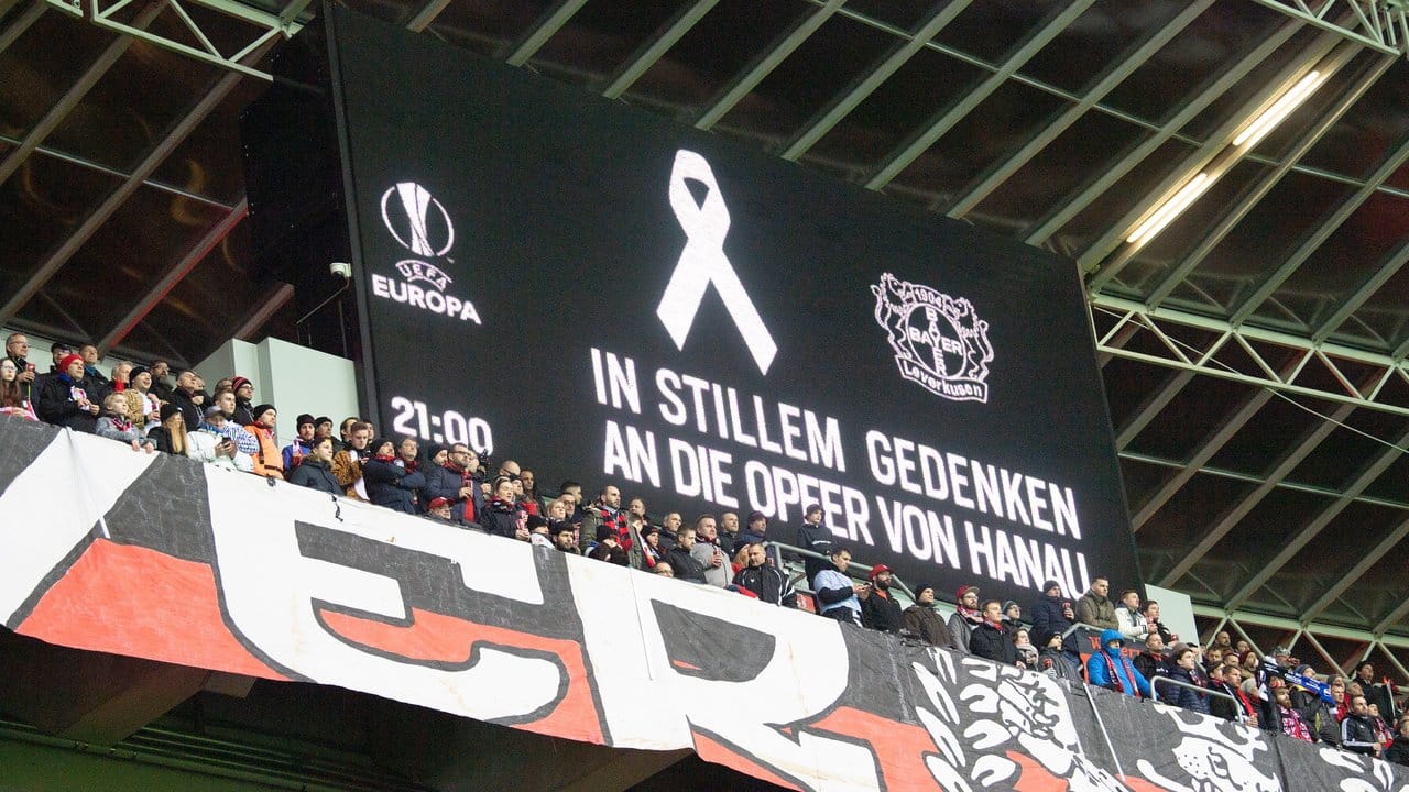 Fans stehen für eine Schweigeminute für die Opfer von Hanau auf der Tribüne.