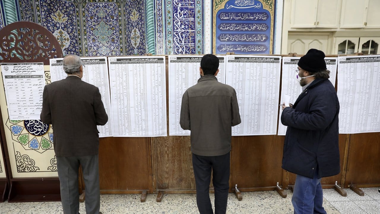 Wähler sehen sich in einem Wahllokal die Listen der Kandidaten an.