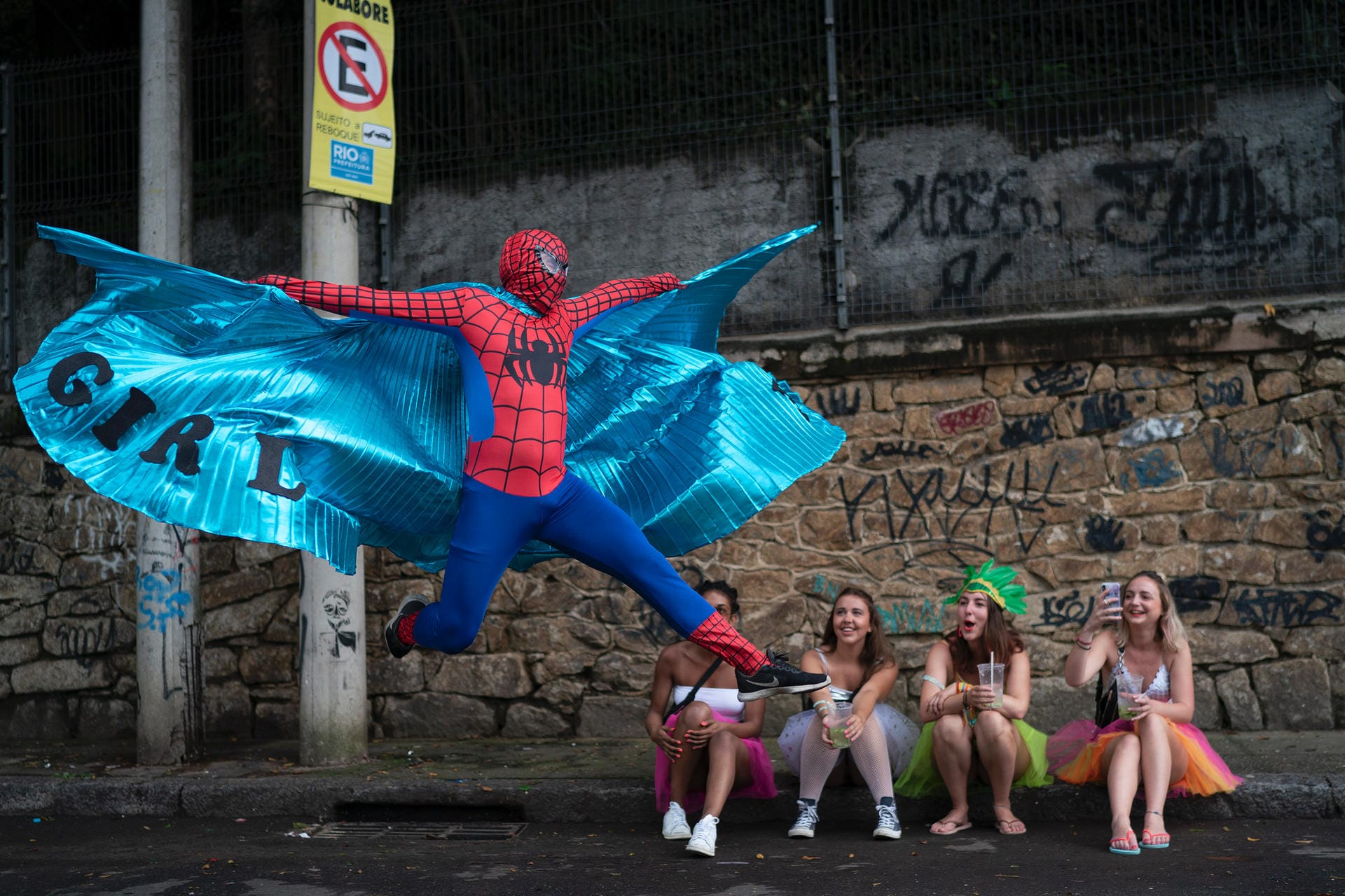 Auch abseits der großen Umzüge wird gefeiert: Ein als Spiderman kostümierter Karnevalsteilnehmer führt vor jungen Frauen einen Sprung auf.
