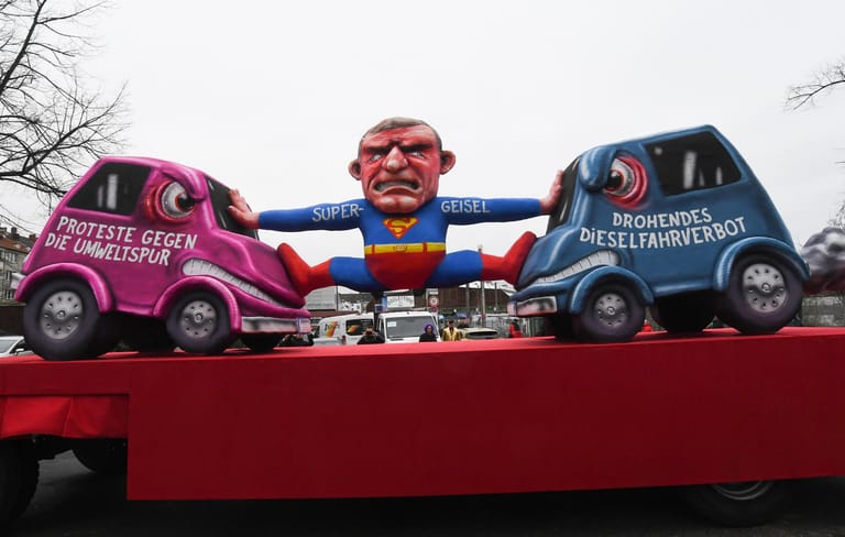 Der Motivwagen "Dieselfahrverbot und Umweltspur": Mit den Rosenmontagszügen erreicht der rheinische Straßenkarneval seinen Höhepunkt.
