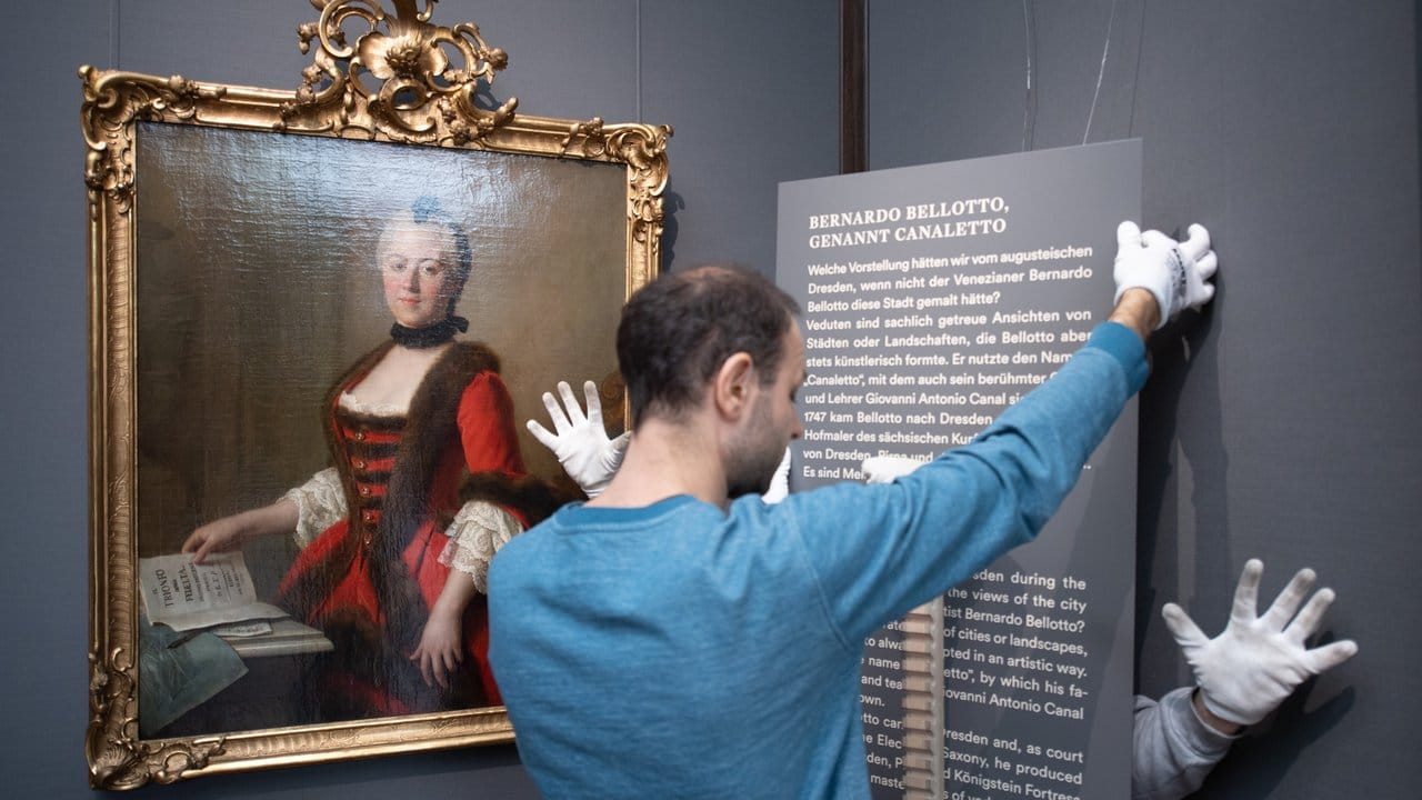 Mitarbeiter der Staatlichen Kunstsammlungen hängen eine Texttafel neben dem Ölgemälde "Maria Antonia von Bayern" von Pietro Antonio Graf Rotarie auf.