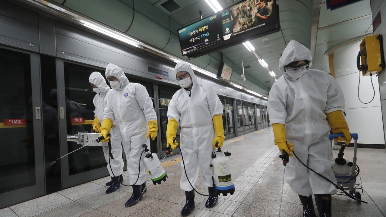 Arbeiter in Schutzkleidung versprühen in einer U-Bahn-Station in Seoul Desinfektionsmittel.