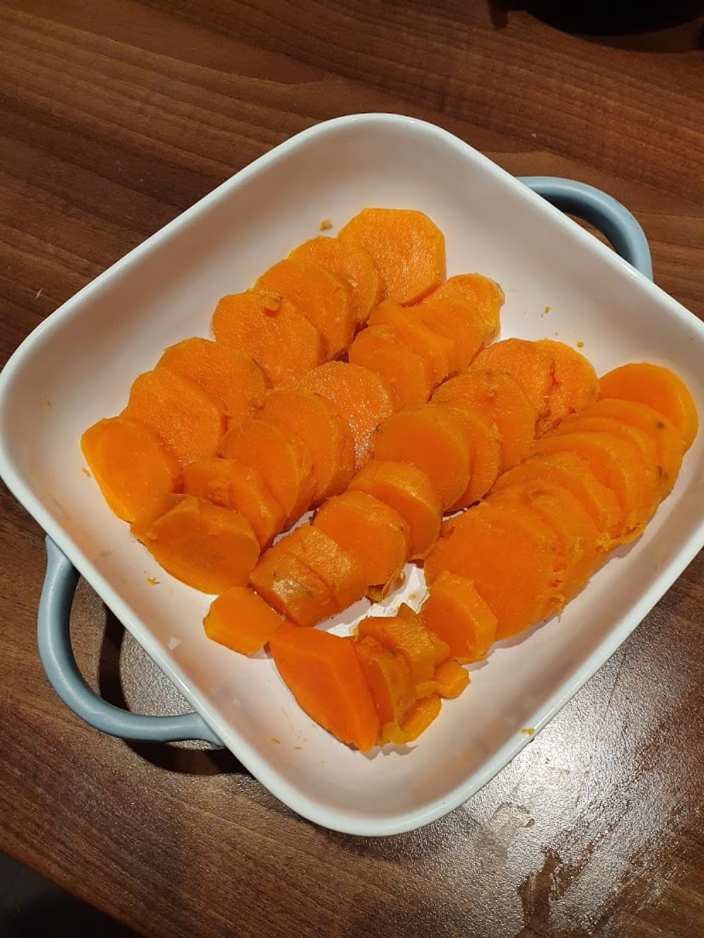 Schneiden Sie die weichen Süßkartoffeln in Scheiben und reihen Sie sie in einer backofenfesten Form auf.