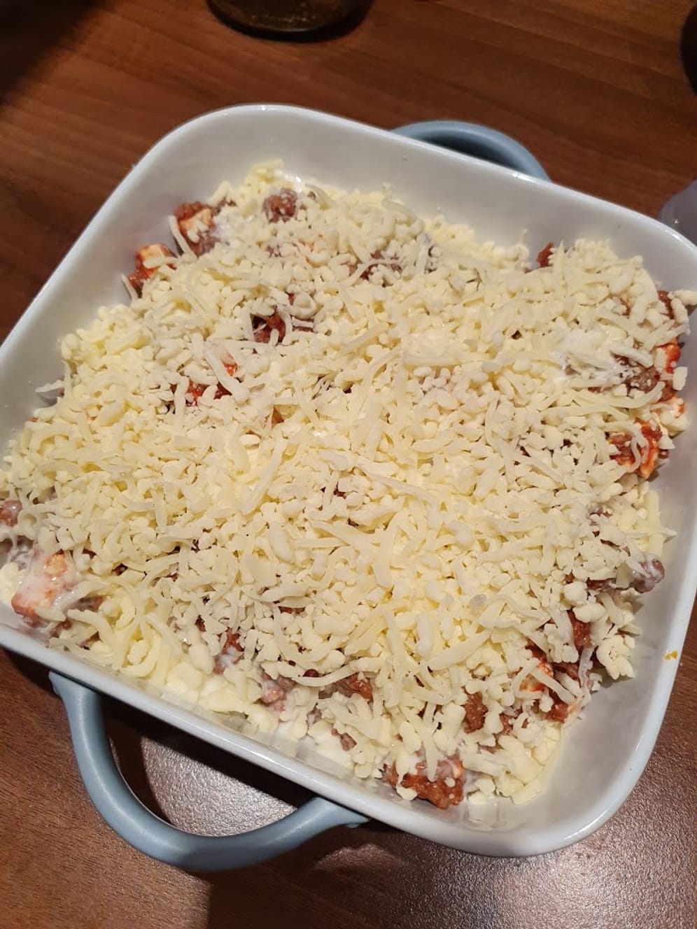 Übergießen Sie den Auflauf am Ende mit der Sahne und streuen Sie den Mozzarella darüber.