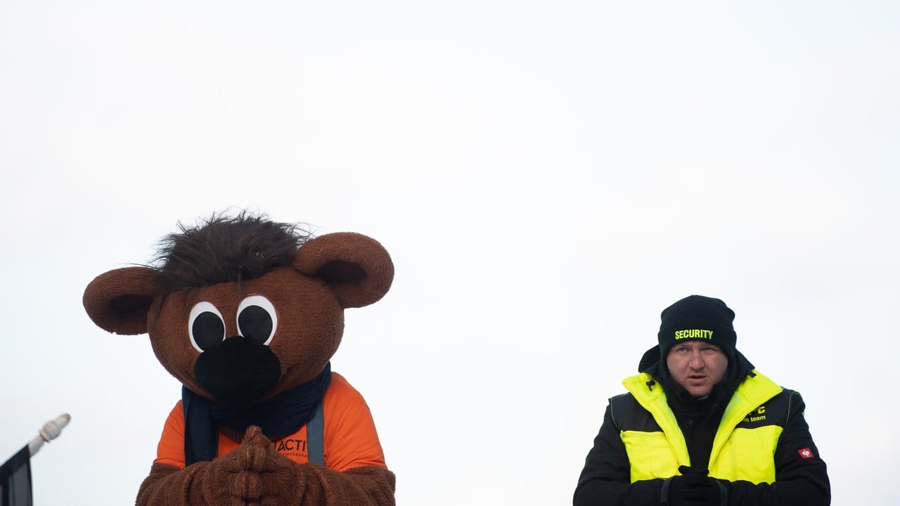 WM-Maskottchen Bobby und ein Sicherheitsmann beobachten die Zieleinfahrt in Altenberg.