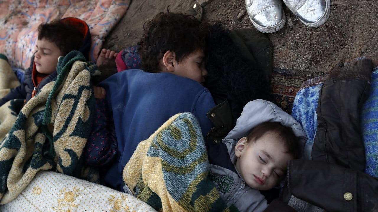 Kinder liegen schlafend auf dem Boden am Ufer des Flusses nahe der türkisch-griechischen Grenze.