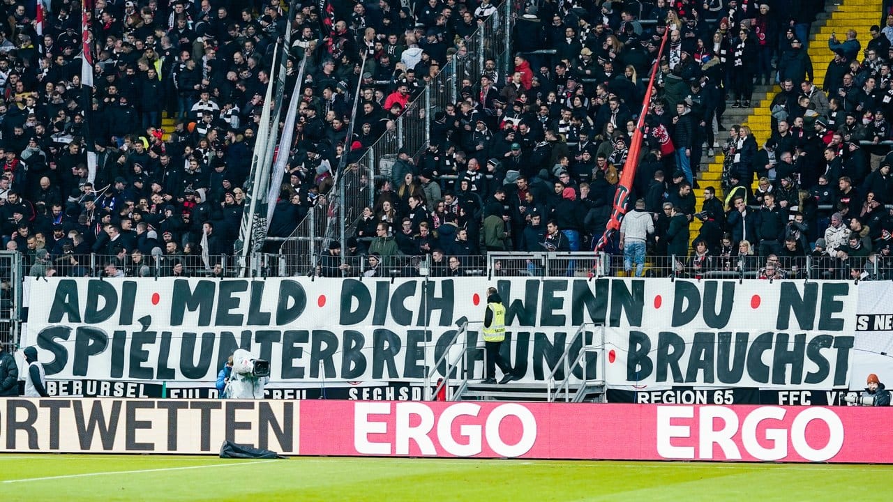 Banner mit der Aufschrift "Adi, meld dich wenn du ne Spielunterbrechung brauchst" sind vor dem Spiel im Stadion zu sehen.