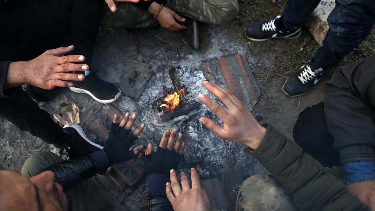 Migranten sitzen nahe der türkisch-griechischen Grenze um ein Lagerfeuer herum und versuchen, sich zu wärmen.