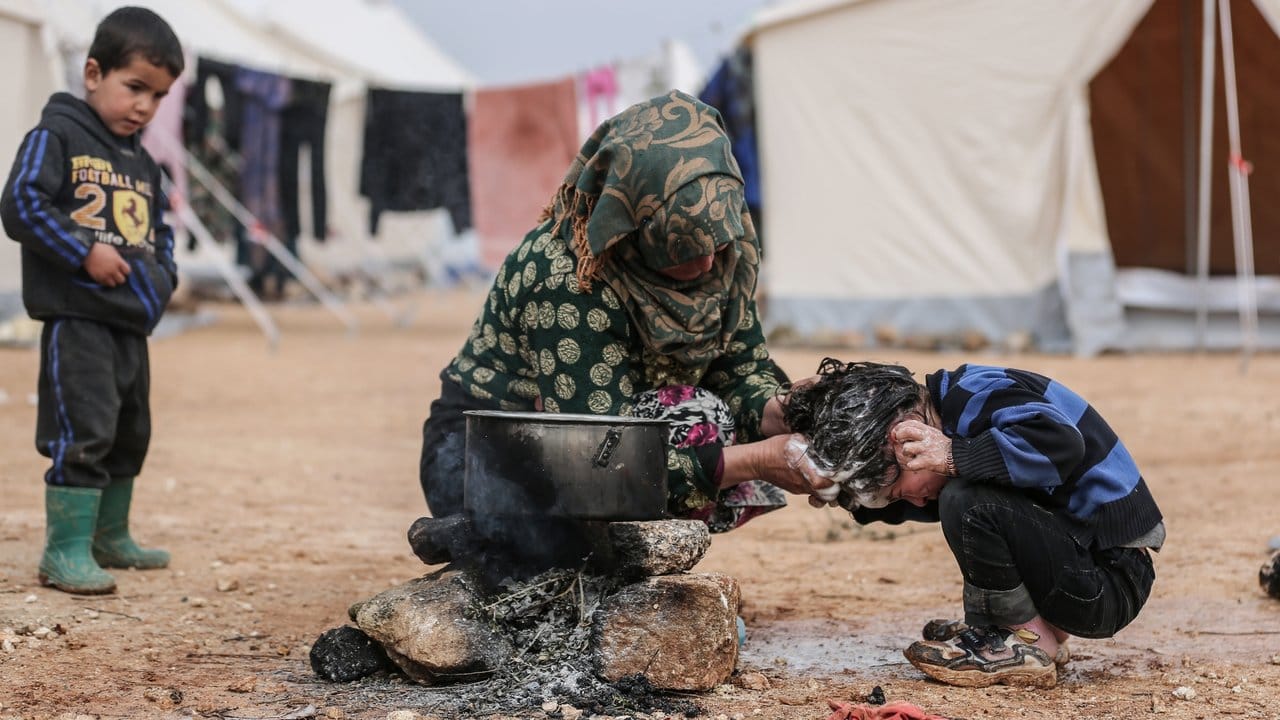 Eine Syrerin wäscht ihr Kind in einem Behelfslager für Familien, die durch Bombenangriffe vertrieben wurden.