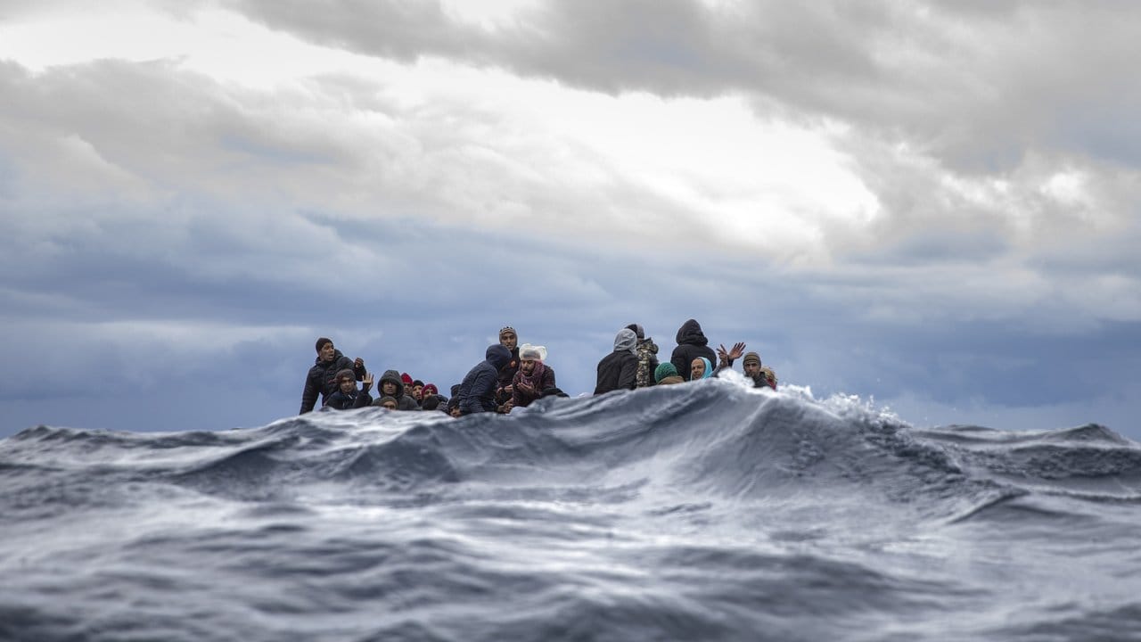 Männer aus Marokko und Bangladesch sitzen in einem überfüllten Holzboot im Mittelmeer vor der Küste von Libyen und warten auf die nahenden Retter der Organisation "Open Arms".
