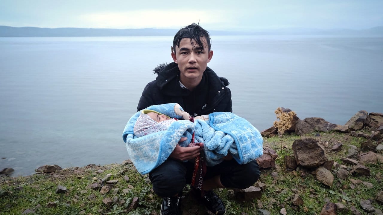 Ein Migrant hält ein Baby an der Küste der griechischen Insel Lesbos, nachdem er mit einem Schlauchboot von der Türkei aus über das Mittelmeer gekommen ist.