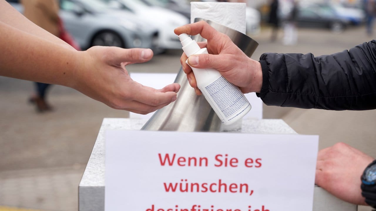 Ein Mitarbeiter der Messegesellschaft desinfiziert auf dem Messegelände einer regionalen Automesse in Koblenz auf Wunsch die Hände der Ausstellungsbesucher.