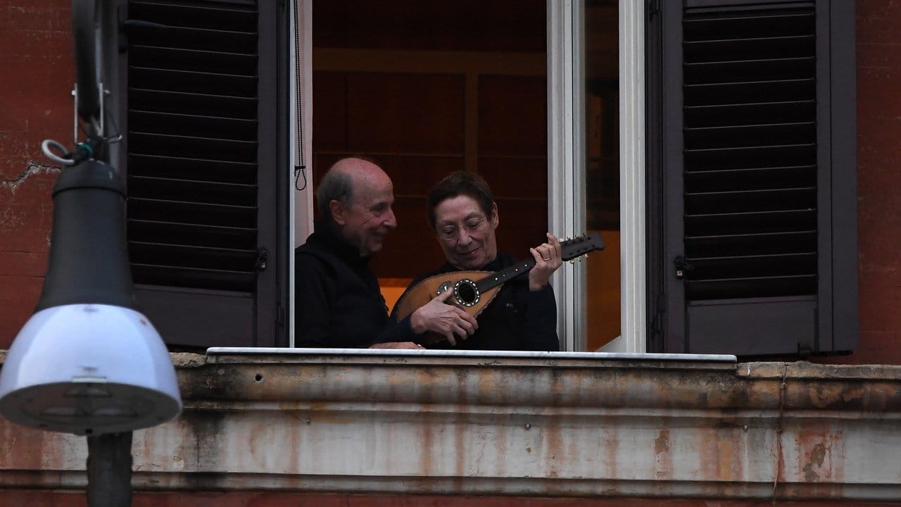 Ein Mann und eine Frau mit einem Instrument an einem geöffneten Fenster in Rom.