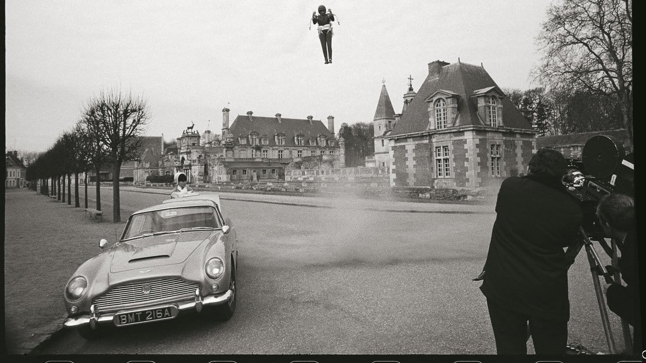 Szene aus "Feuerball" (1965) mit Sean Connery: Die französische Spionin Mademoiselle Laporte wartet am Aston Martin DB5 auf James Bond, der gerade mit einem Raketenrucksack landet.