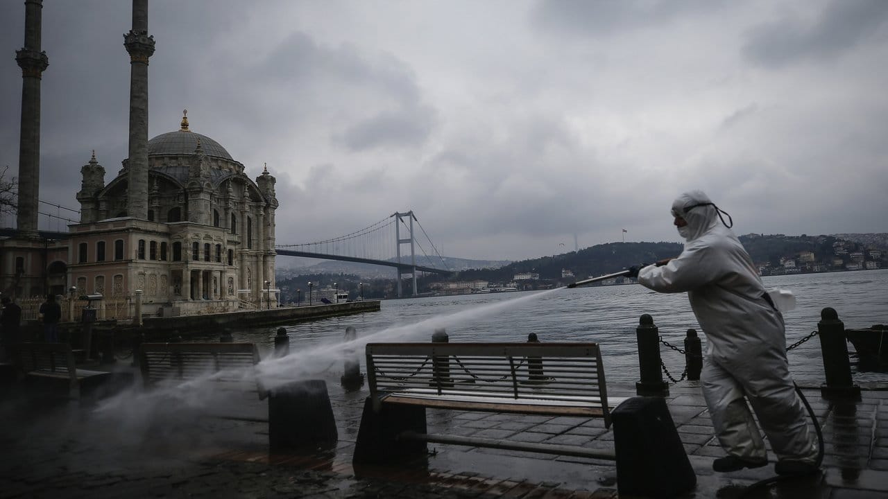 Ein Gemeindeangestellter in Istanbul versprüht Wasser in einem Schutzanzug.