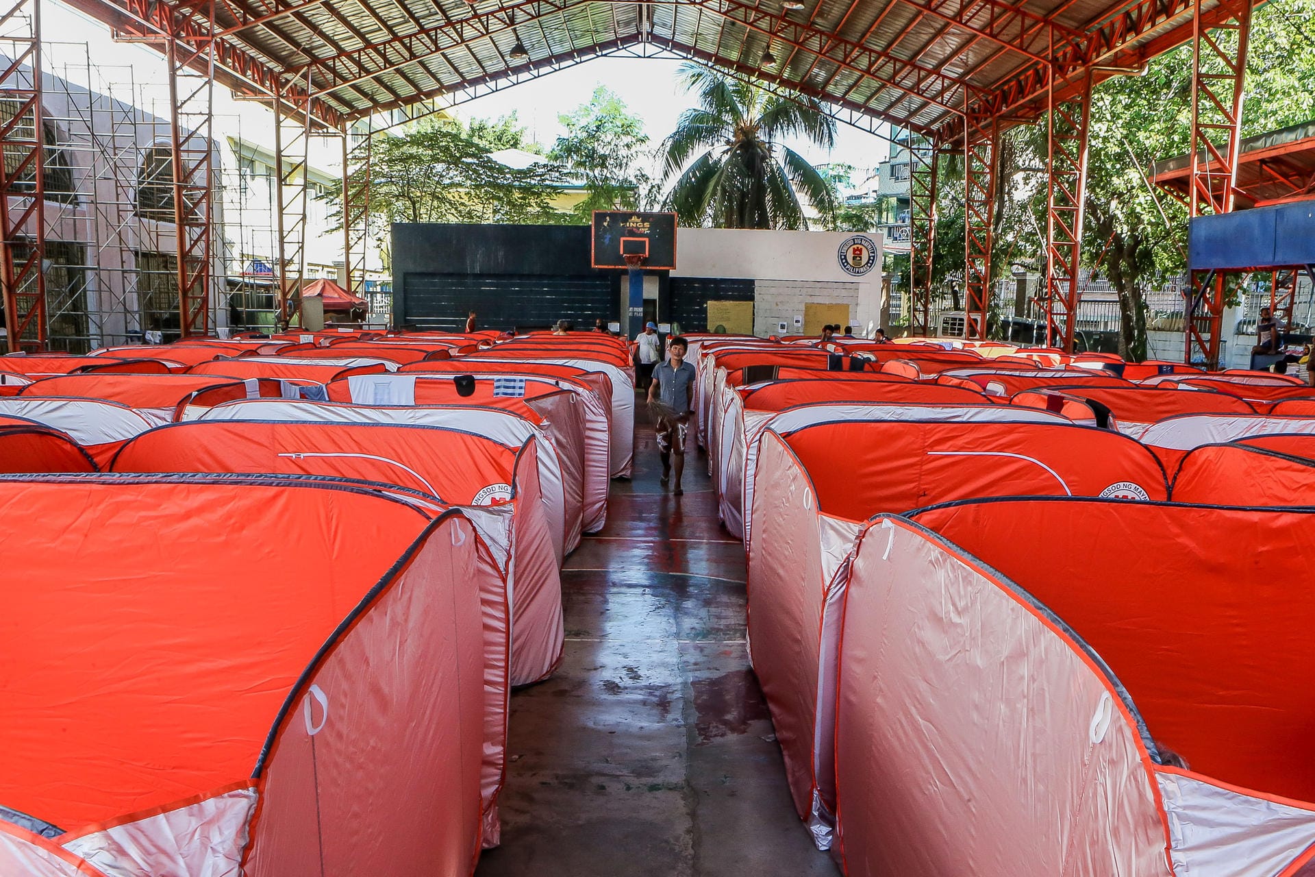 Philippinen, Manila: Ein Mann geht zwischen modularen Zelten, welche für Straßenbewohner auf einem Basketballplatz aufgestellt wurden, um die weitere Verbreitung von Covid-19 zu verhindern.