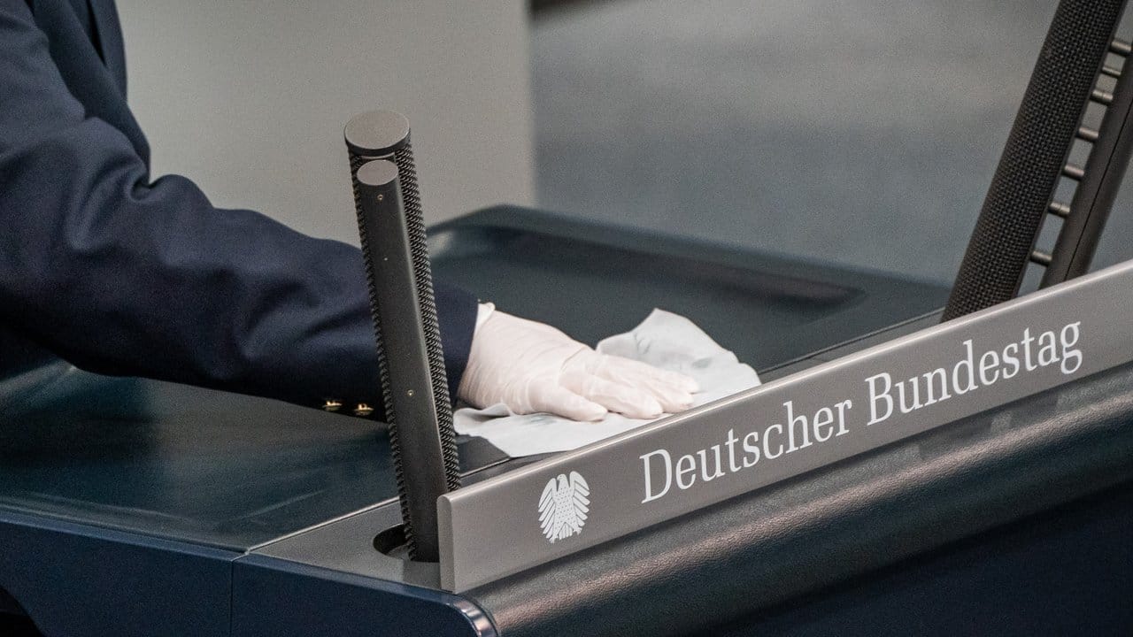 Vorbeugemaßnahme: Eine Saaldiener desinfiziert das Rednerpult im Bundestag. Vorbeugemaßnahme: Eine Saaldiener desinfiziert das Rednerpult im Bundestag.