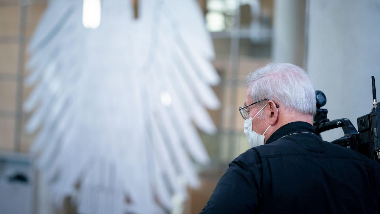 Nicht nur Politiker gehen auf nunmal sicher: Ein Kameramann mit Mundschutz filmt die Sitzung des Bundestages. Nicht nur Politiker gehen auf nunmal sicher: Ein Kameramann mit Mundschutz filmt die Sitzung des Bundestages.