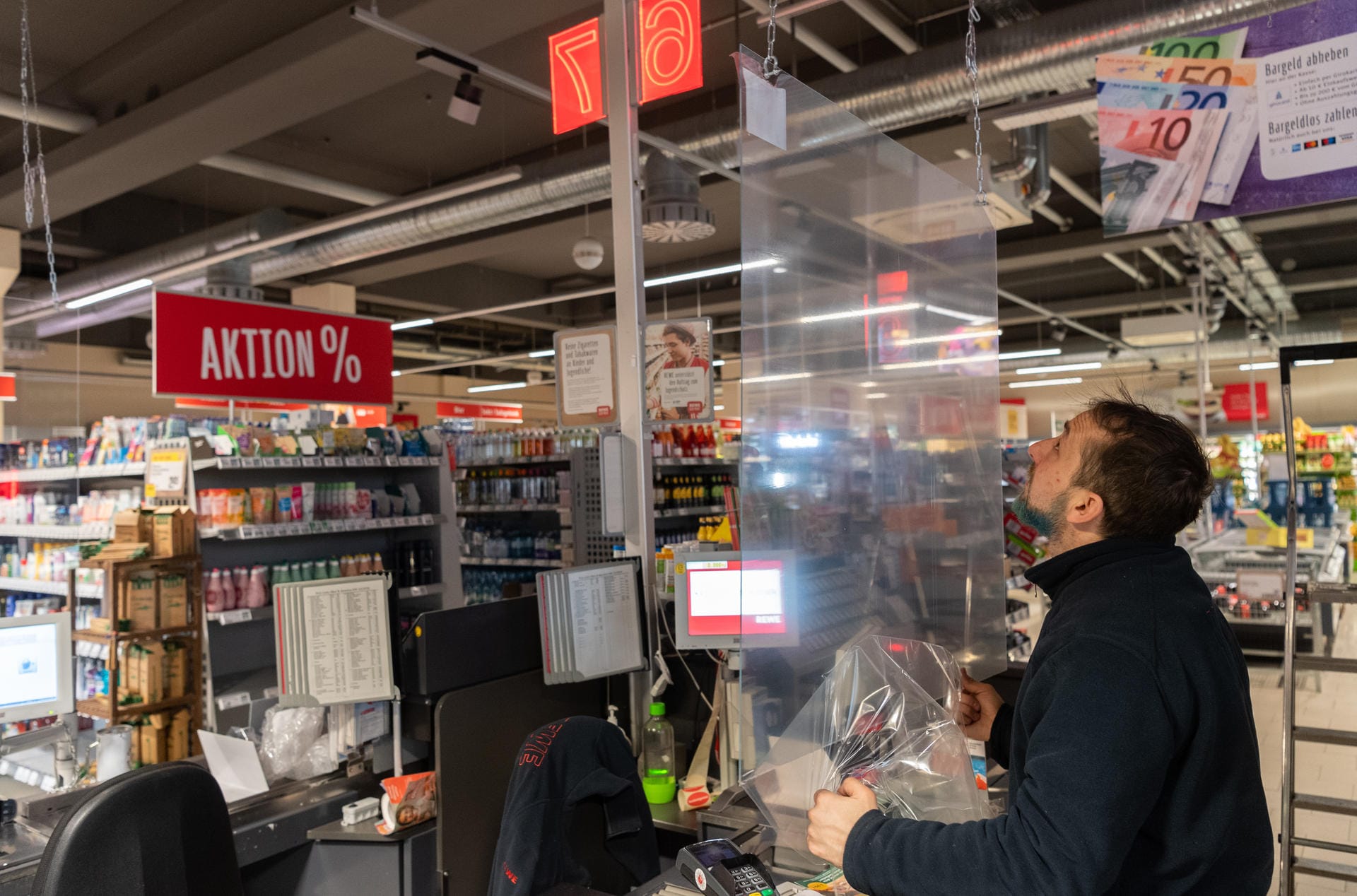 Dresden: Im Kampf gegen die Ausbreitung des neuartigen Coronavirus installiert ein Mitarbeiter in einem Supermarkt eine Plexiglasscheibe an der Kasse.