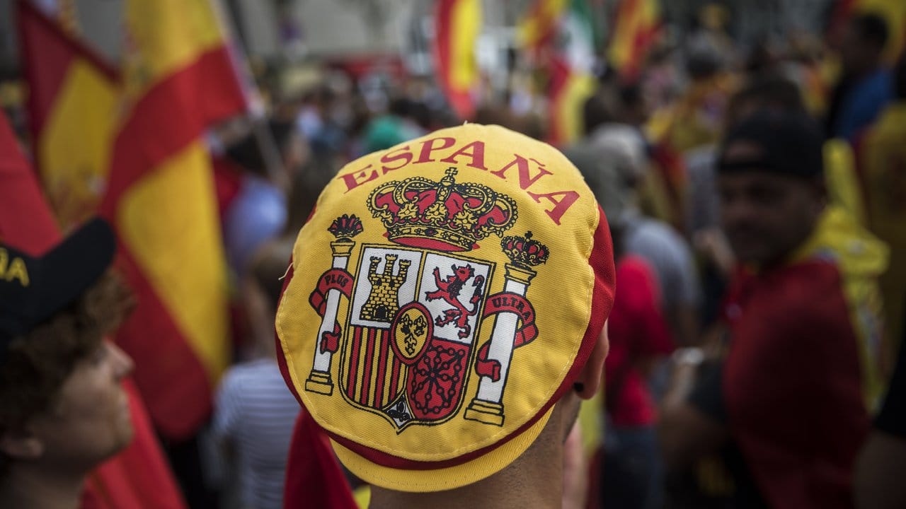 Ein Mann mit einer Mütze auf der das spanische Wappen zu sehen ist, nimmt an einer Demonstration, die während des Nationalfeiertags in Spanien stattfindet, teil.