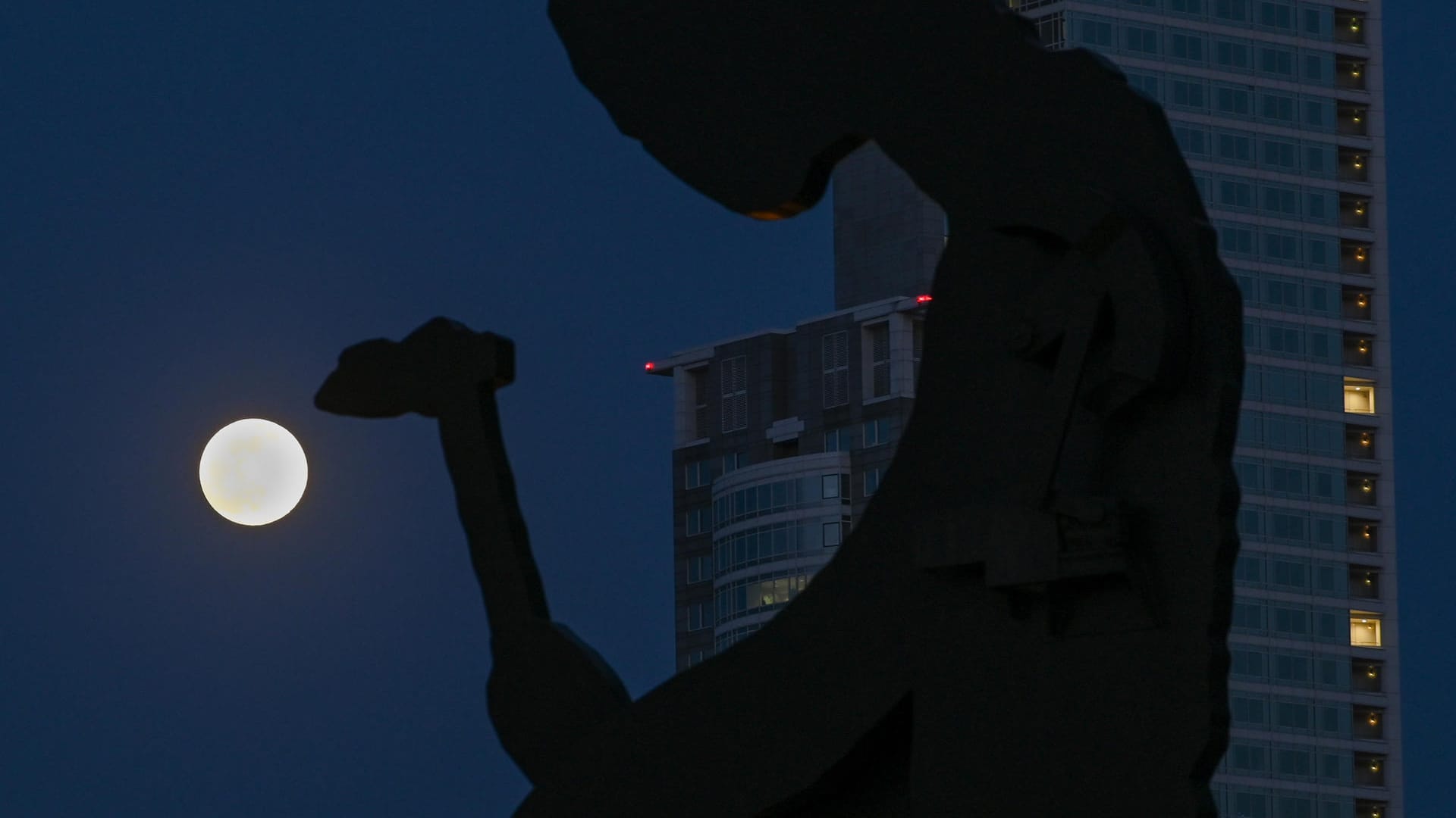 Frankfurt/Main: Der Mond steht als sogenannter Supermond hinter dem berühmten "Hammering Man", ein Kunstwerk des US-amerikanischen Künstlers Jonathan Borofsky.