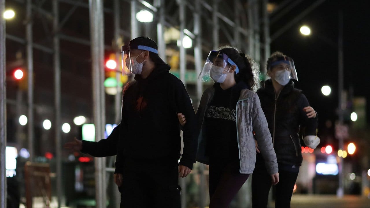 New Yorker gehen mit Mundschutz und Gesichtsmaske eine Straße entlang. New Yorker gehen mit Mundschutz und Gesichtsmaske eine Straße entlang.
