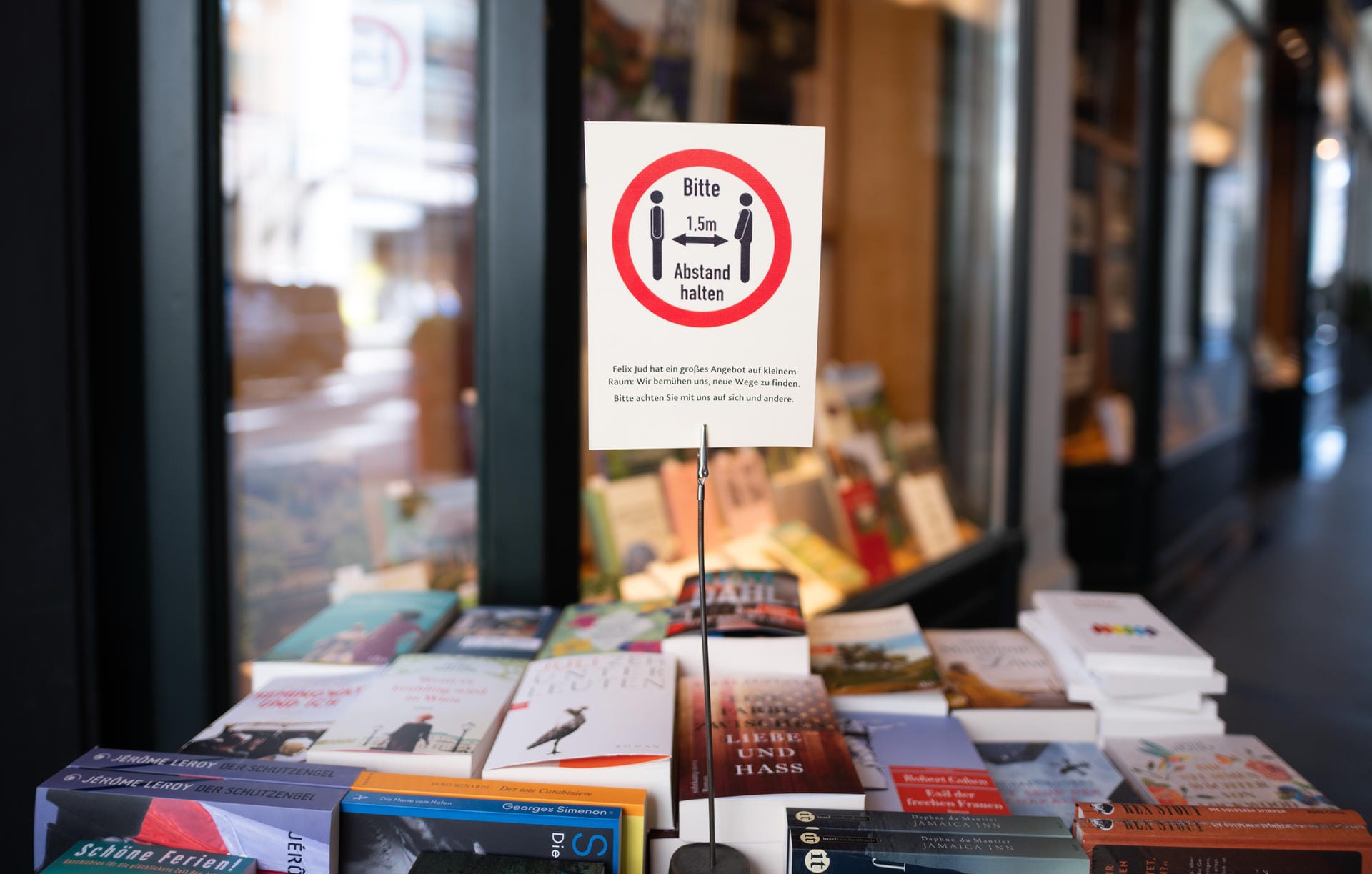 Ein Schild mit einem Hinweis auf die Abstandsregeln zwischen Büchern: Buchhandlungen, wie hier am Jungfernstieg in Hamburg, gehören zu den Läden, die wieder öffnen dürfen. Doch Kunden müssen weiterhin Abstand zueinander halten.