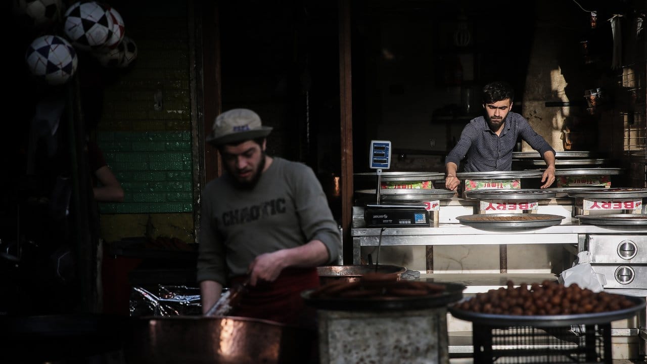 Syrische Verkäufer bereiten auf einem Straßenmarkt traditionelle Süßigkeiten zu.
